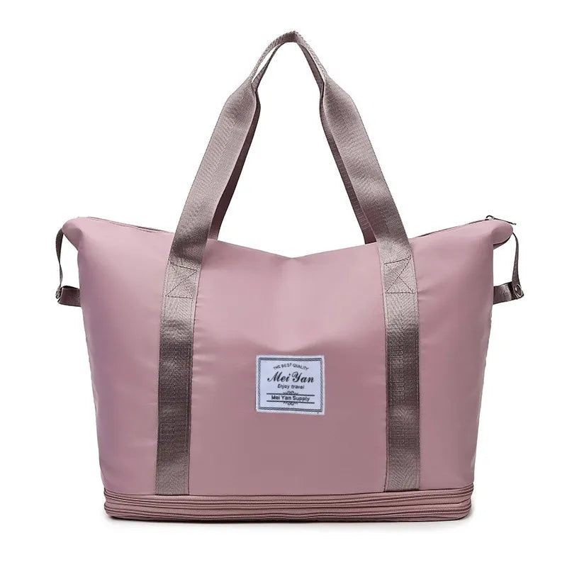Dusty pink large duffle bag with two top handles, side straps, and front logo patch
