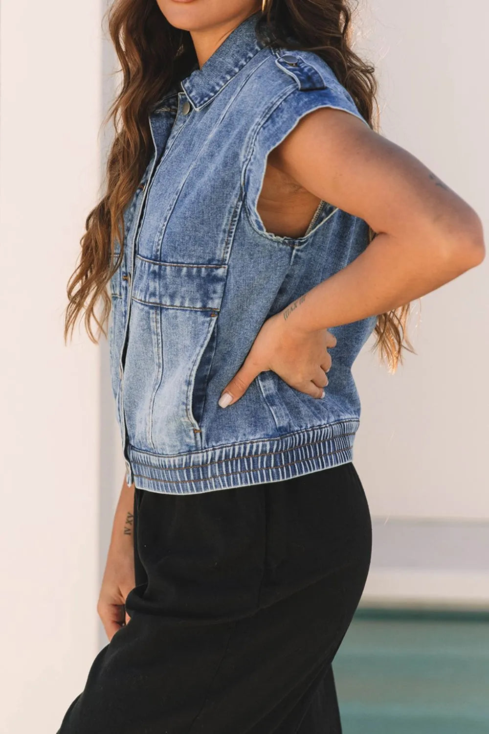 Medium-wash denim button-up cap sleeve jacket with shoulder yoke and adjustable button tab