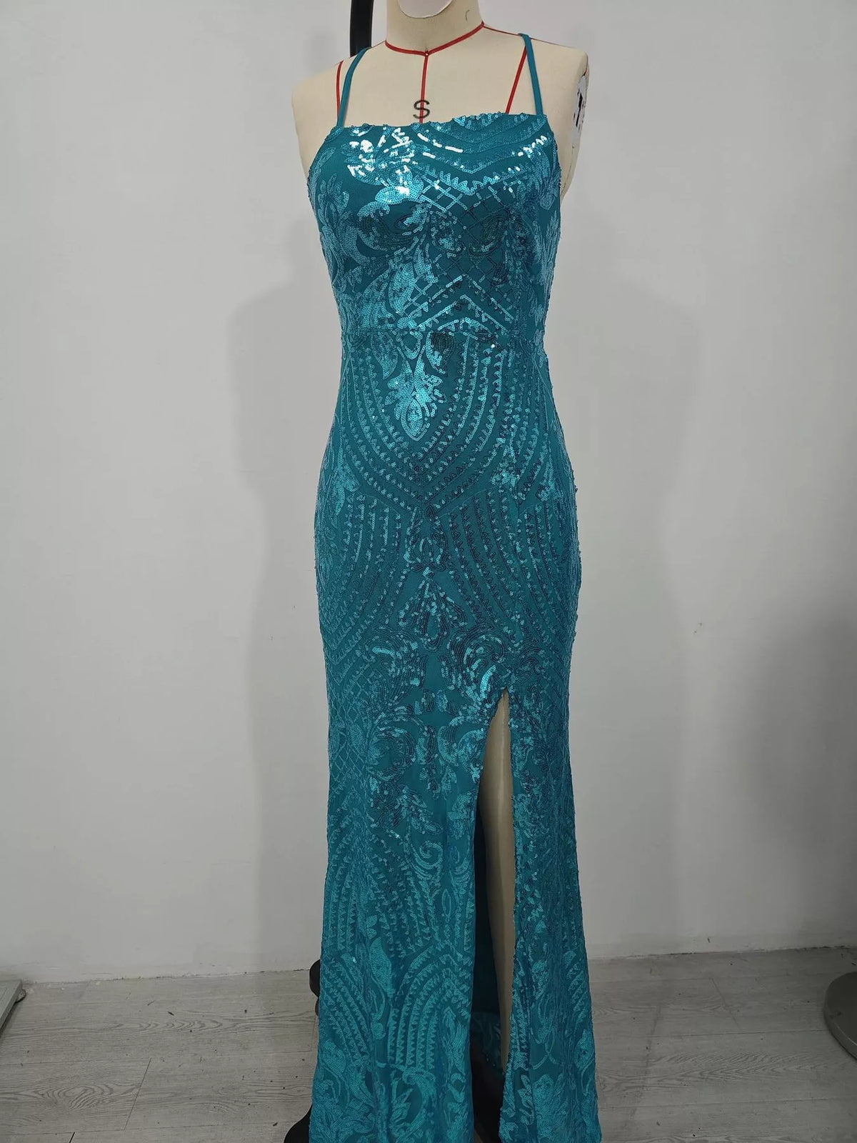 Turquoise sequin backless evening dress on mannequin with front slit