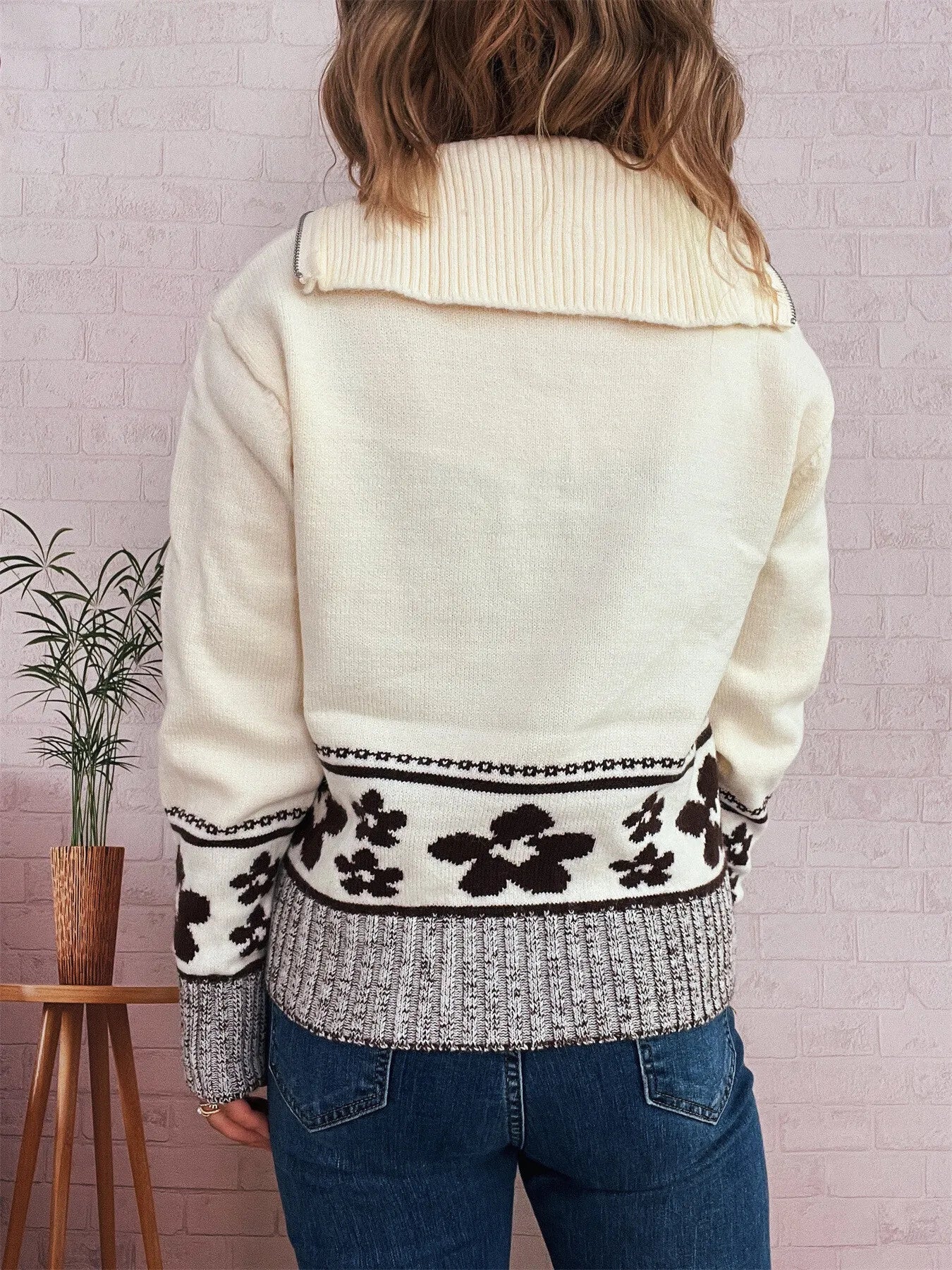 White back view sweater with high ribbed collar and black flower knit band at the hem