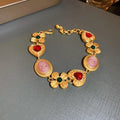 Gold-tone vintage charm bracelet with red heart and pink oval rhinestone links