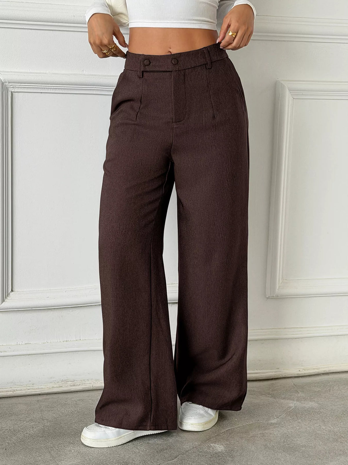 Brown high-waisted wide-leg pants with button closure and front pockets.