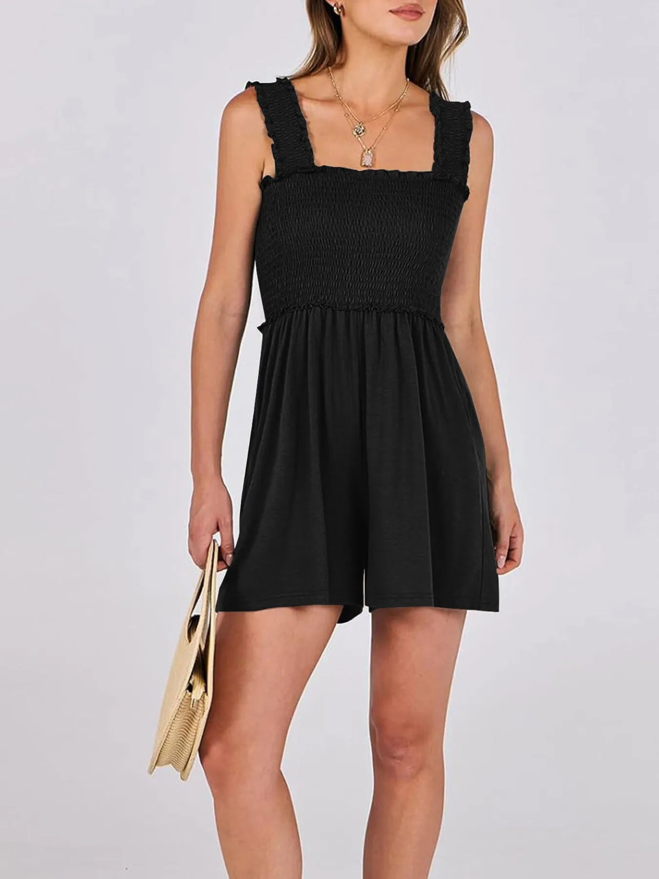 Black sleeveless smocked romper with square neckline, ruffled straps, and short gathered skirt