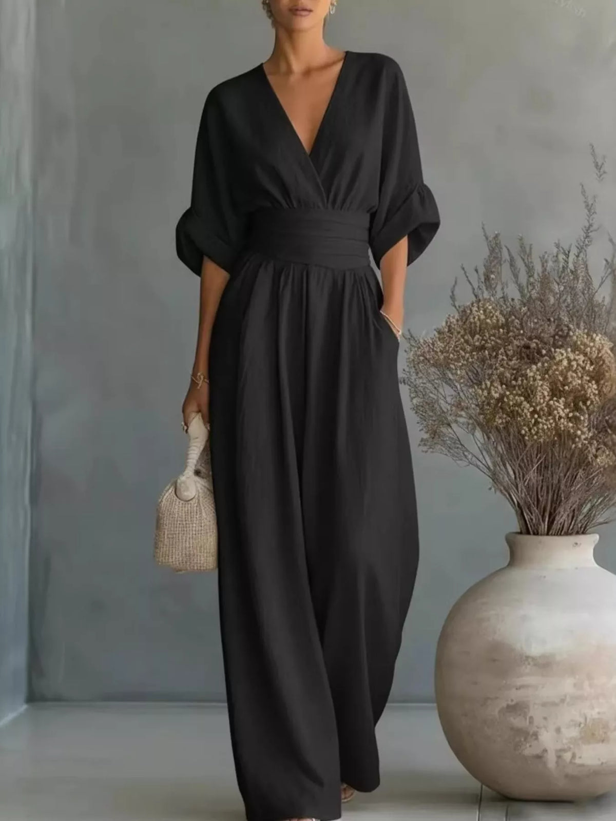 Black V-neck wide-leg jumpsuit with ruched waist and half sleeves.