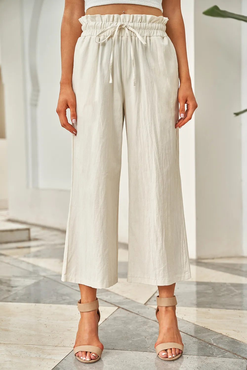 Ivory drawstring paperbag waist wide-leg pants with gathered waist and cropped hem.
