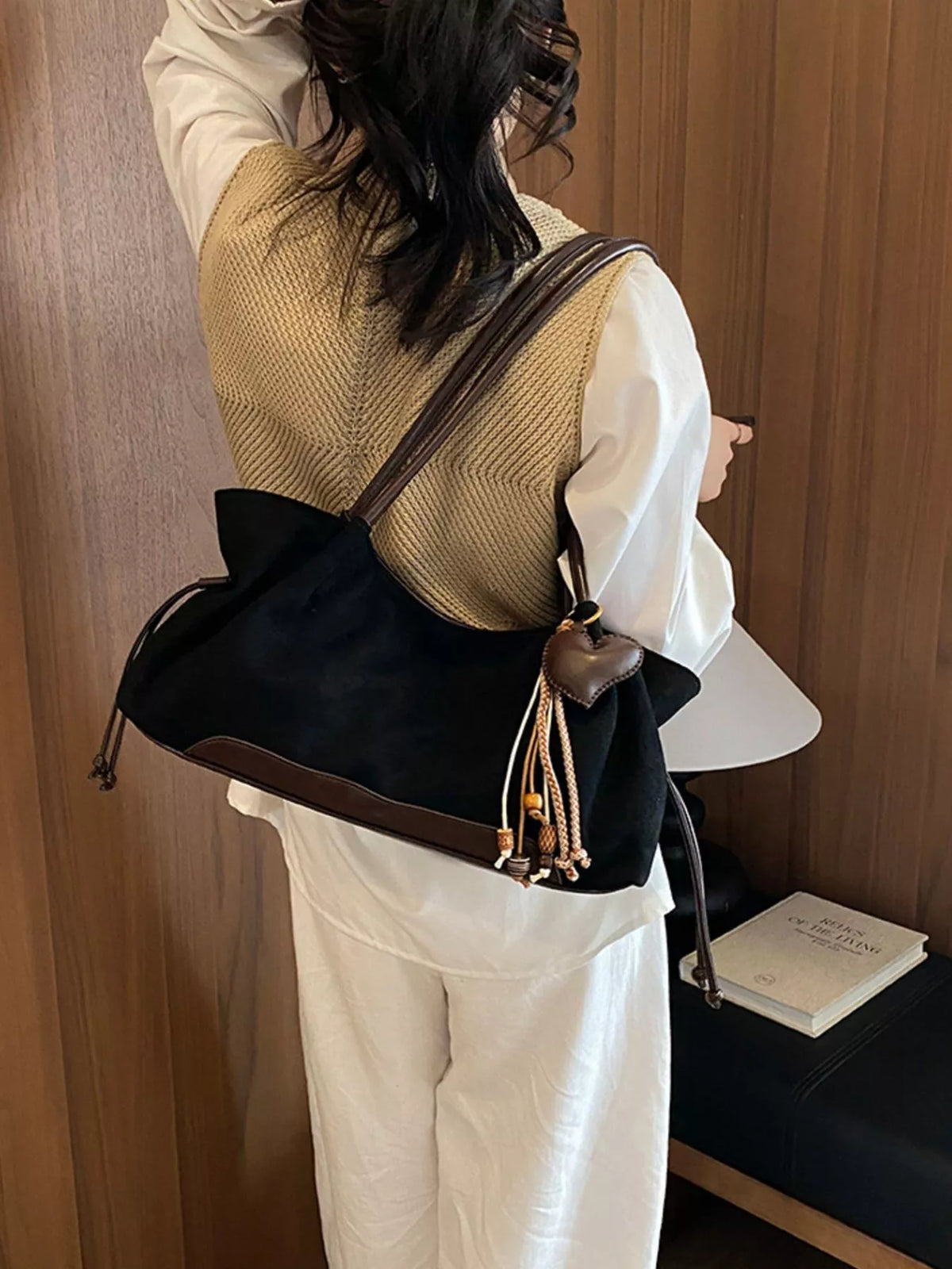 Black suede drawstring shoulder bag with heart charm front and braided tassel pull details
