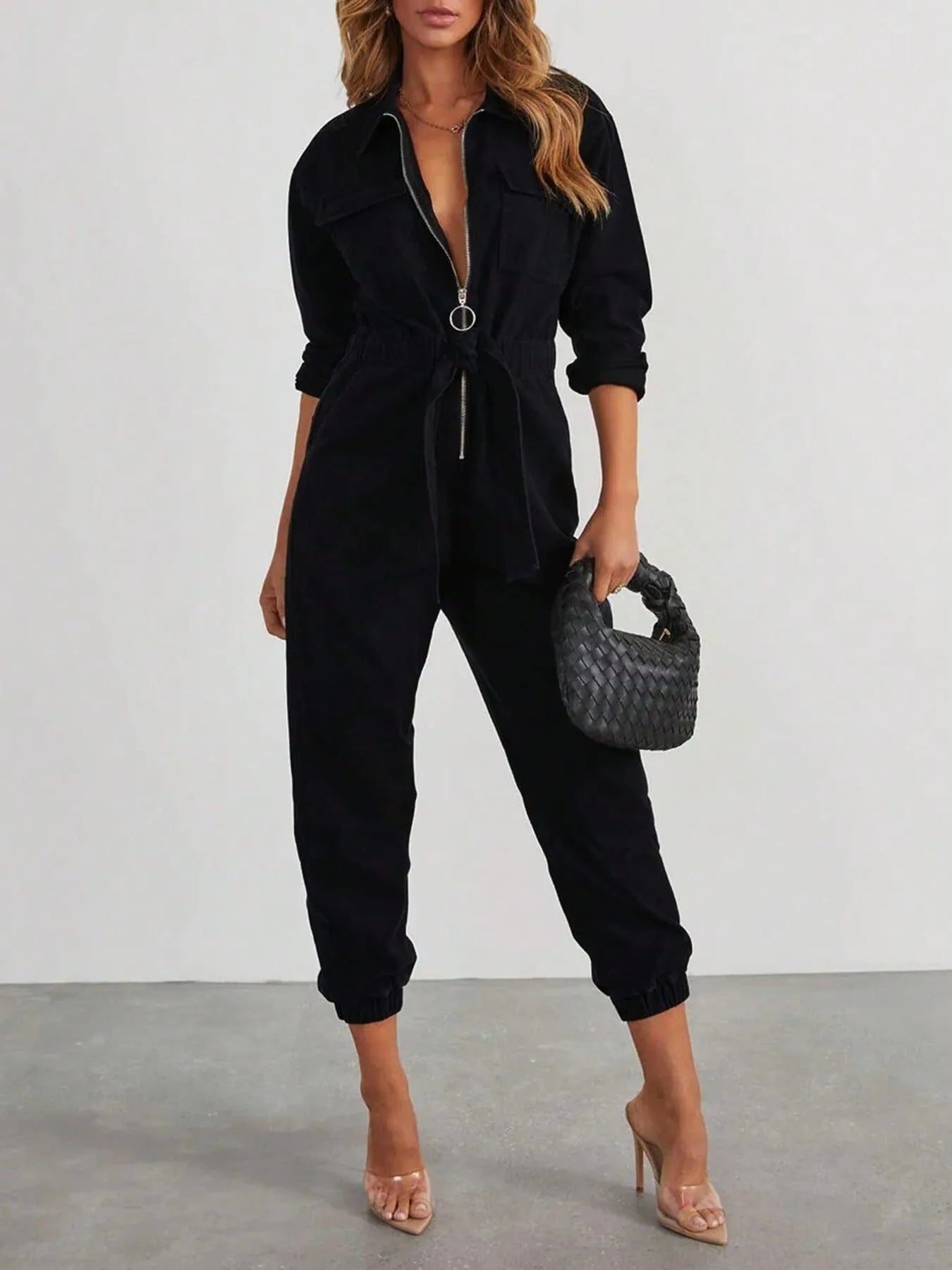 Black long-sleeve zip-front jumpsuit with front pockets, tie waist, and cuffed ankles