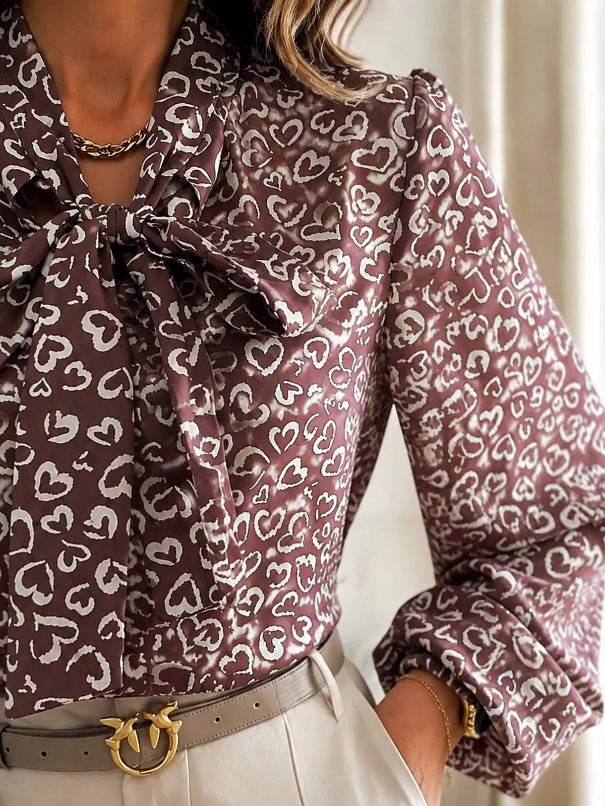 Close-up of printed bow-tie neck long-sleeve blouse with heart pattern
