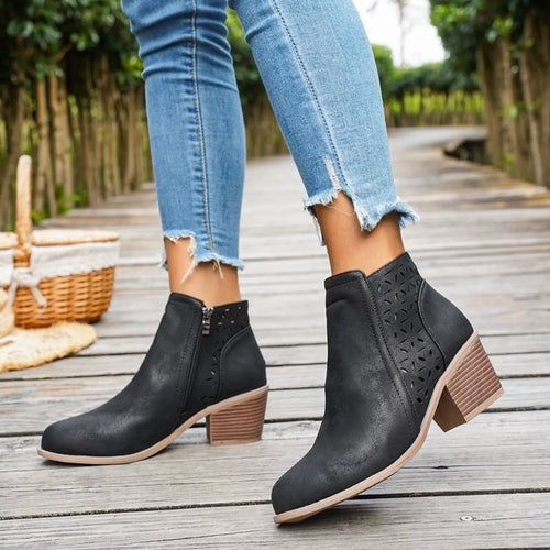 Black ankle boots with block heel and geometric cutout side detail.