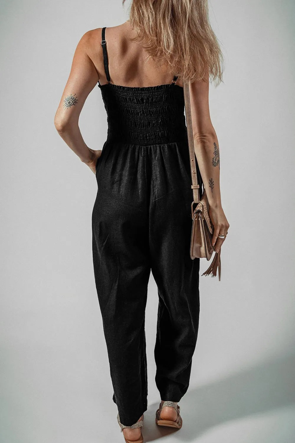 Black smocked-back spaghetti strap wide-leg jumpsuit with gathered waist and wide legs