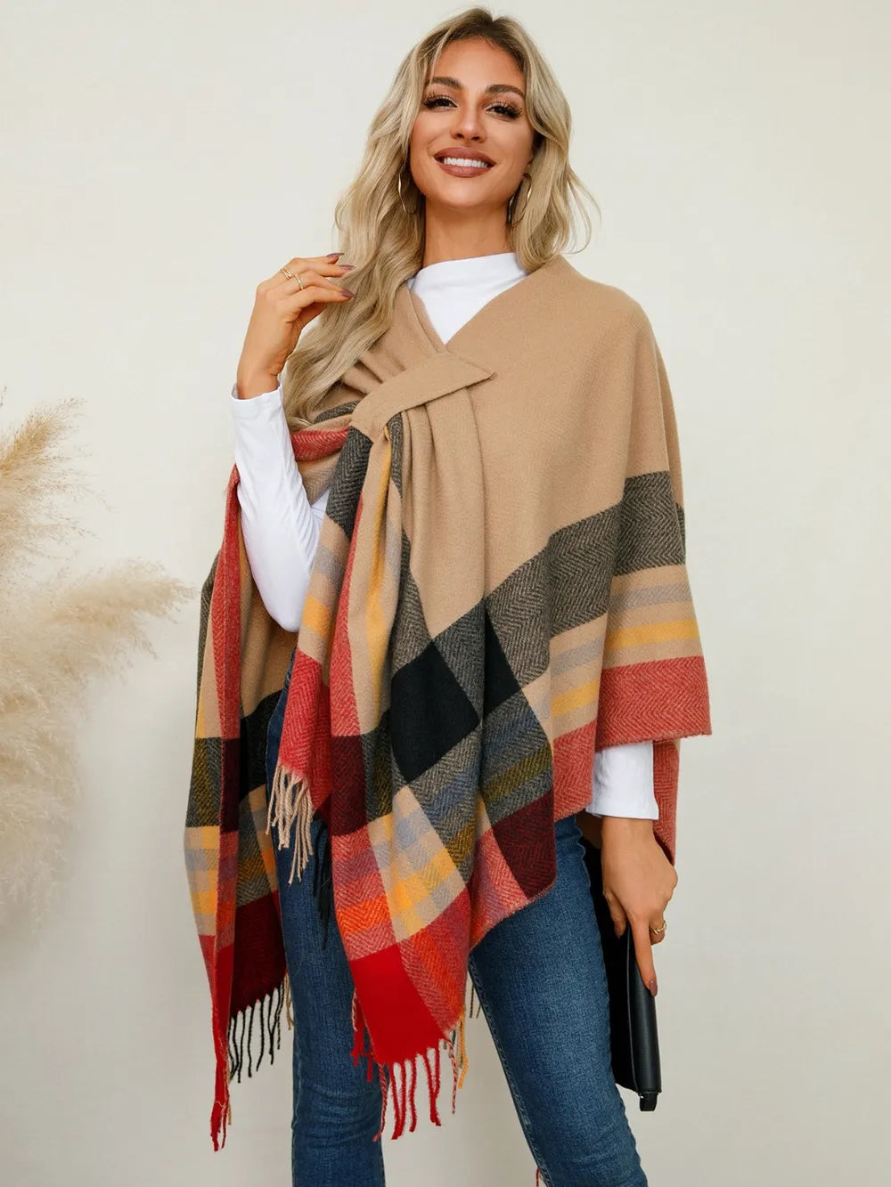 Plaid contrast poncho with fringe trim in tan, black, red, and navy stripes