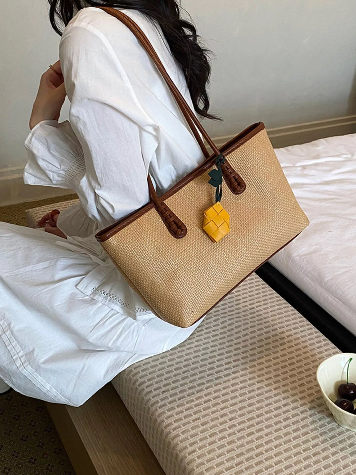 Beige leather shoulder bag with brown handles and yellow charm detail