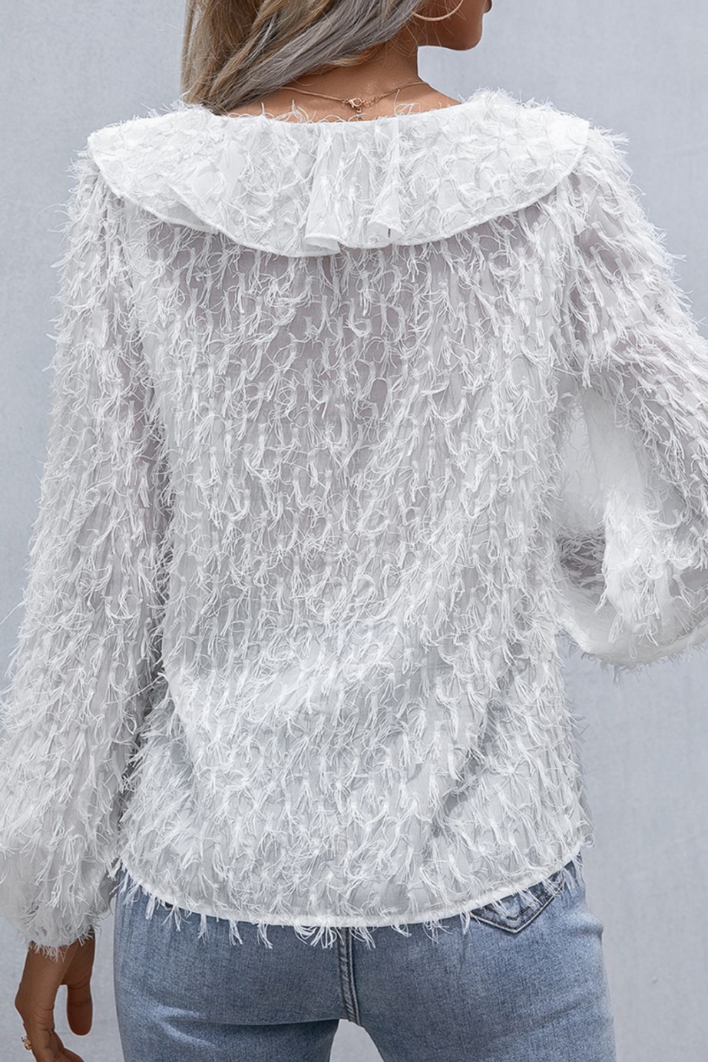 White ruffle-collar blouse with balloon sleeves and textured fringe hem, back view