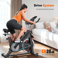 Indoor cycling exercise bike with console, belt-drive flywheel, and cushioned seat in home