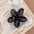 Black glossy flower hair claw clip with five-petal design and plastic barrette back