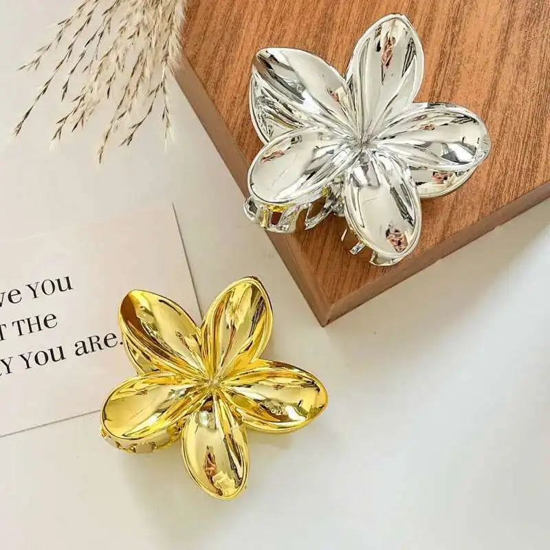 Hawaiian gradient flower hair claw clips on a tray: gold and silver flower shapes