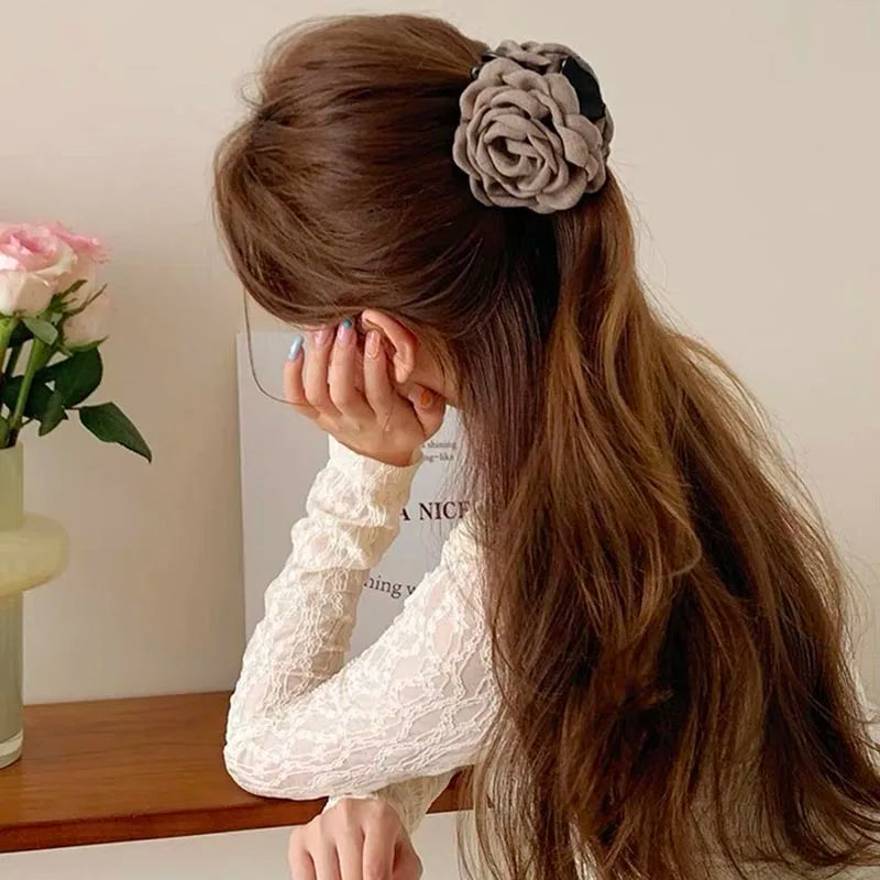 Beige fabric rose hair claw clip with layered petals on long hair