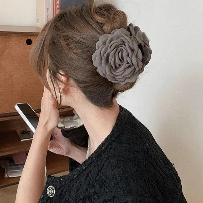 Light gray fabric rose hair claw clip on dark hair with layered petal rosette