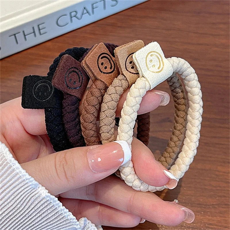 Hair scrunchie set in black, brown, tan, and cream with smile-face logo patches