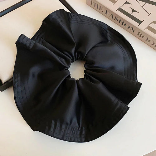 Black satin-like pleated scrunchie with gathered center and ruffle edges