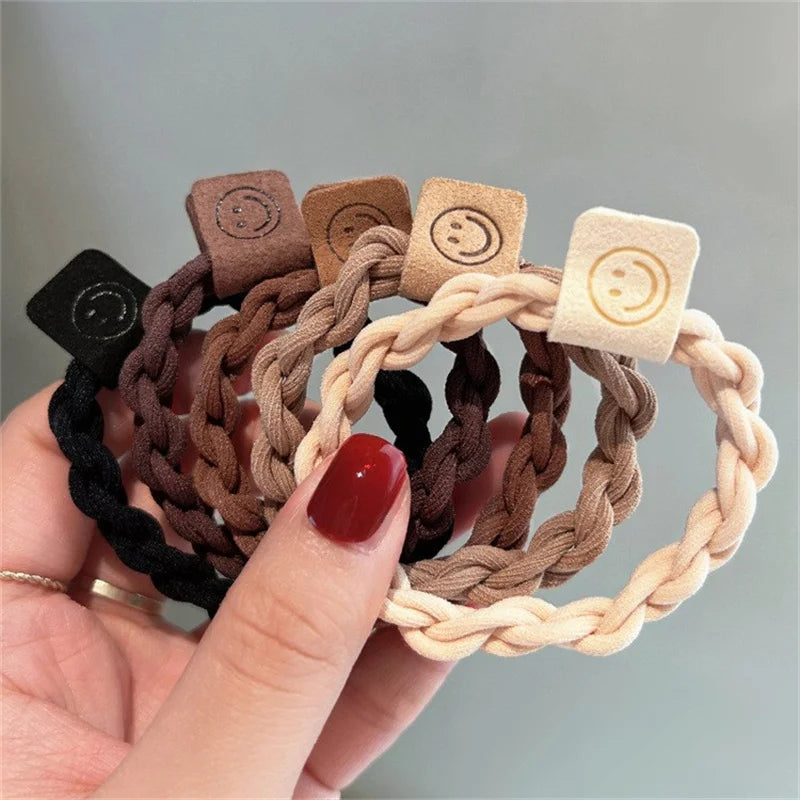 Handheld hair scrunchie set with braided bands and smile-face tags in brown, black, cream