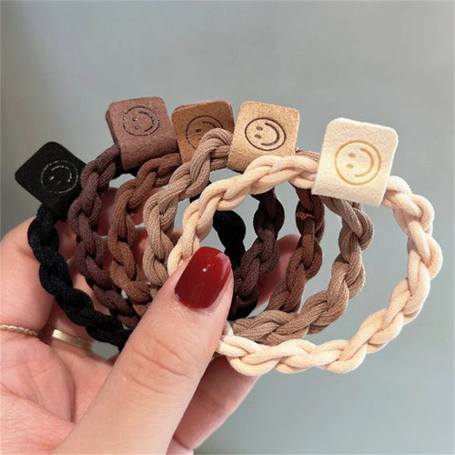 Handheld hair scrunchie set with braided bands and smile-face tags in brown, black, cream