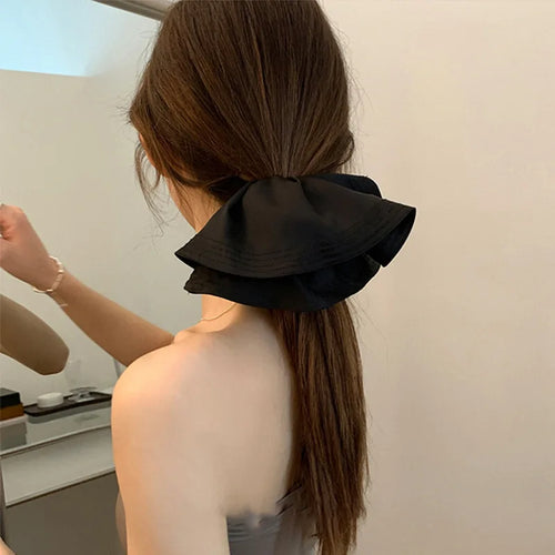 Black pleated large fabric hair scrunchie in a ponytail, ruffled bow shape