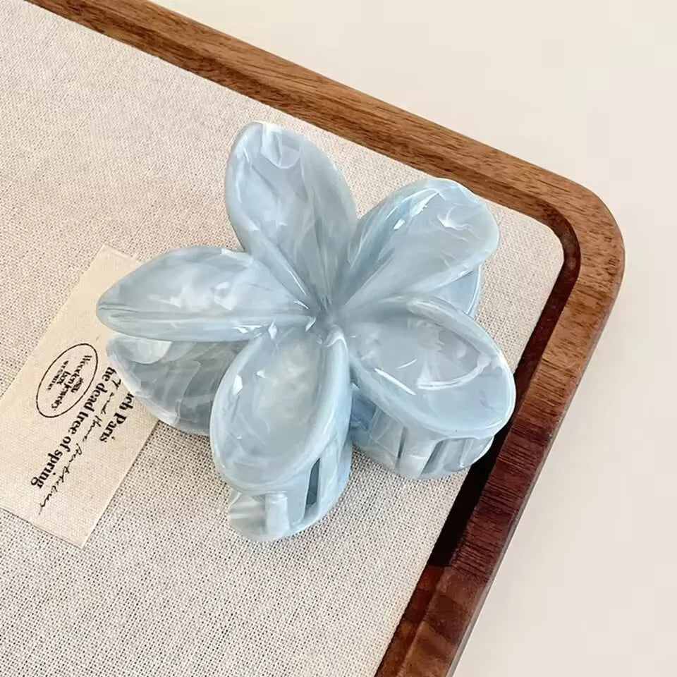 Light blue flower hair claw clip with translucent five-petal design and plastic barrette
