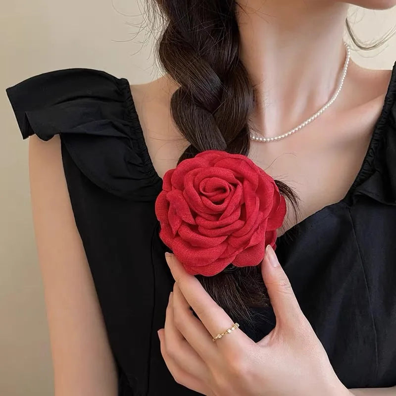 Red fabric rose hair claw clip on dark hair with layered petal rosette design