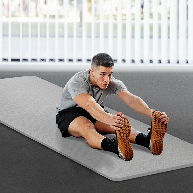 Gray non-slip yoga mat on the floor, rounded corner and textured surface visible