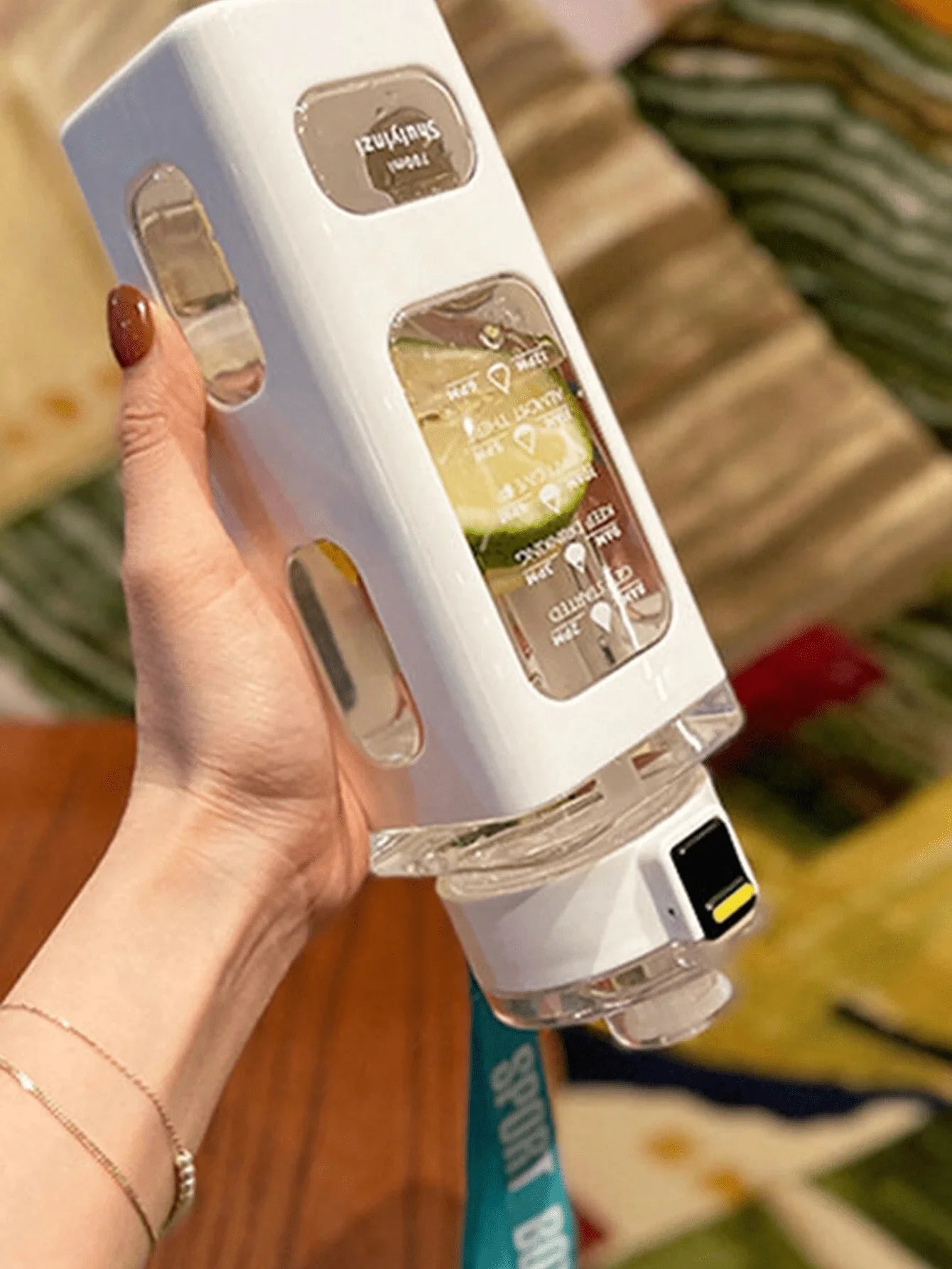 White sports water bottle in hand with straw lid and timetable front panel