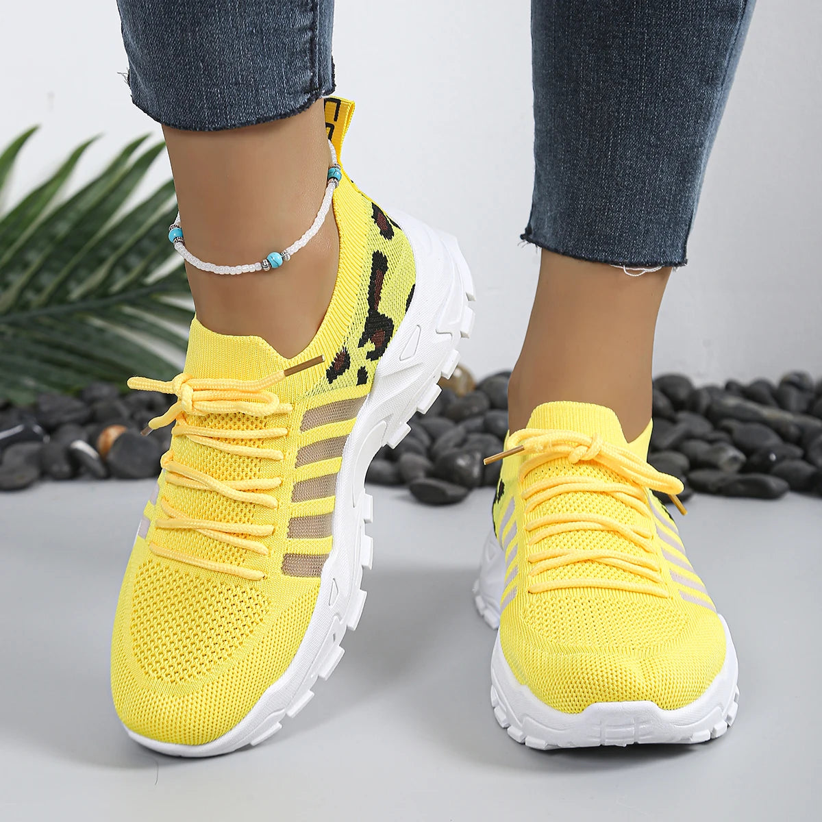 Pair of women's yellow leopard-print athletic sneakers with breathable knit upper and thick white sole