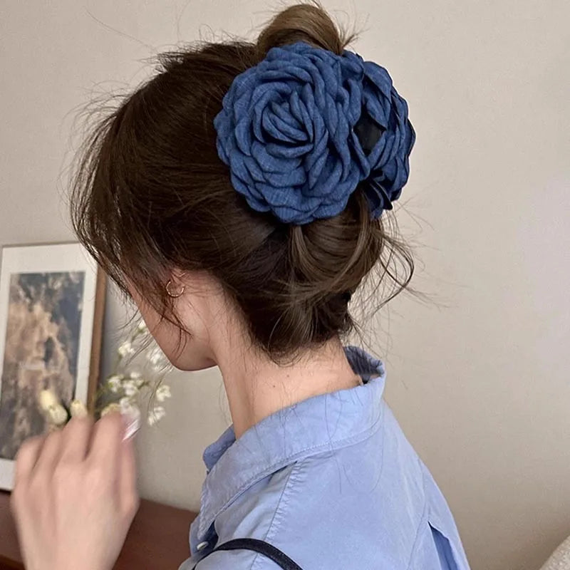 Blue fabric rose hair claw clip with layered petals on dark hair