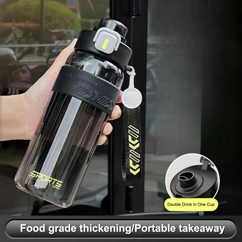 Black and clear sports water bottle with pop-up straw lid and handle, held in hand with strap.