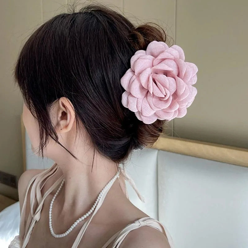 Light pink fabric rose hair claw clip with layered petals on dark hair