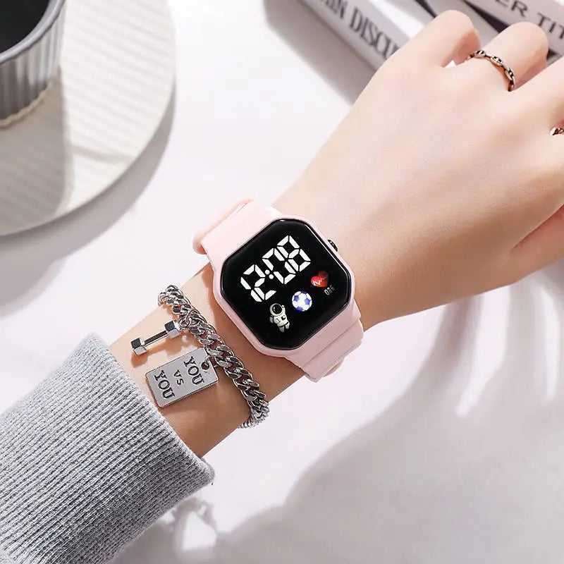 Kids LED digital watch with pink silicone strap on wrist, black square digital display