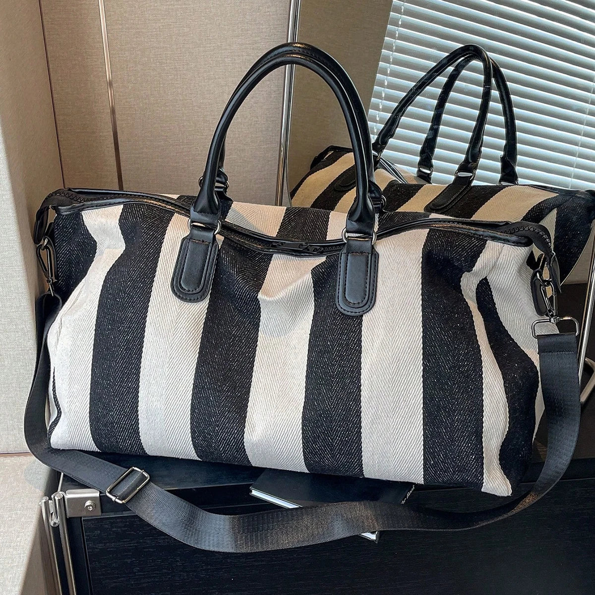 Striped duffle bag with double top handles, side zip pocket, and crossbody strap