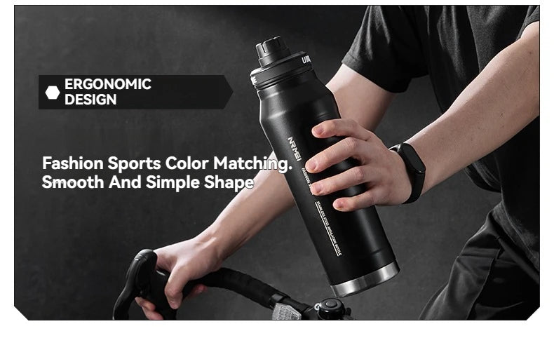 Black insulated stainless steel sports water bottle in a hand with strap handle