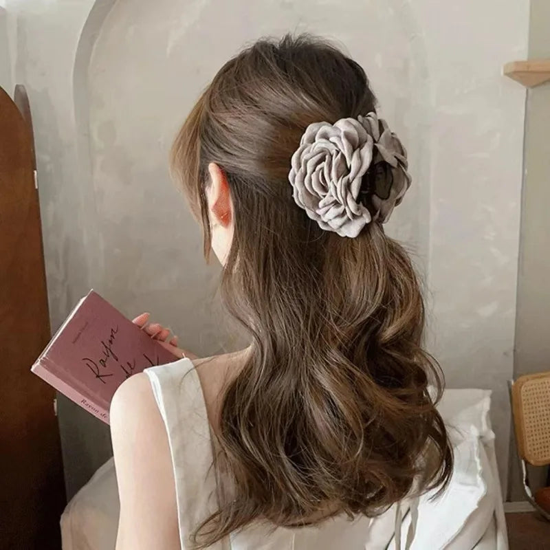 Beige fabric rose hair claw clip with layered petals on wavy hair