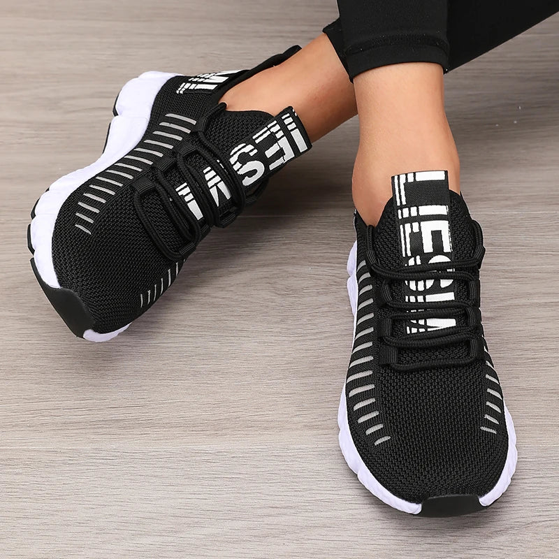 Women’s lightweight running shoes, black knit upper with strap closure and white sole