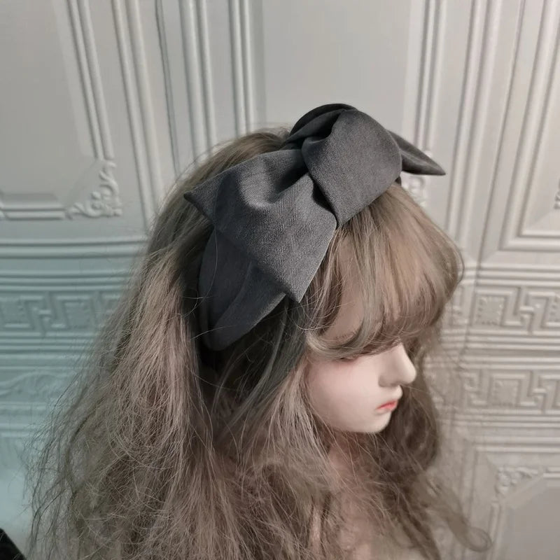 Black wide bow headband with fabric knot, worn on hair