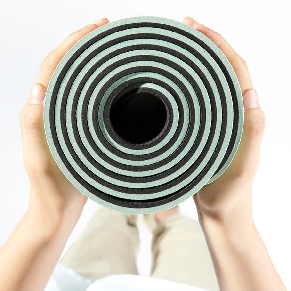 6mm TPE Yoga Mat by Cedar & Moore, mint green and black rolled mat held by hands