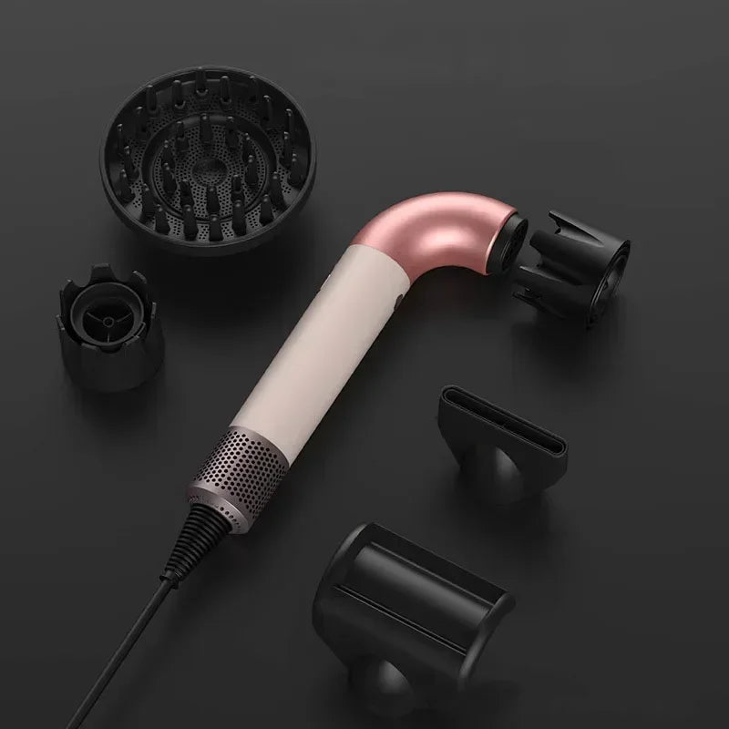 Pink and cream hair dryer with black styling nozzles and diffuser, overhead view