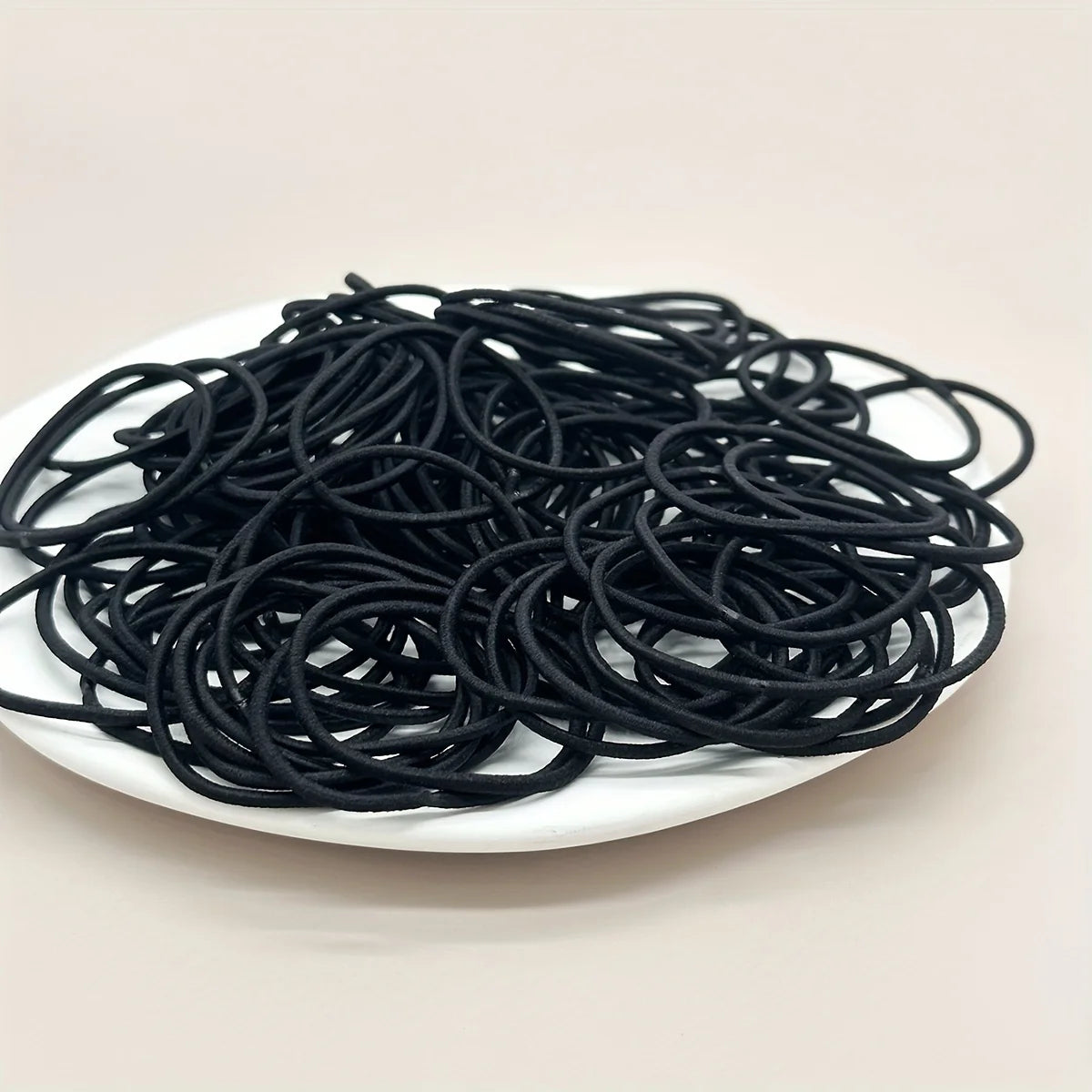 Black hair ties, pile of coiled bands on plate