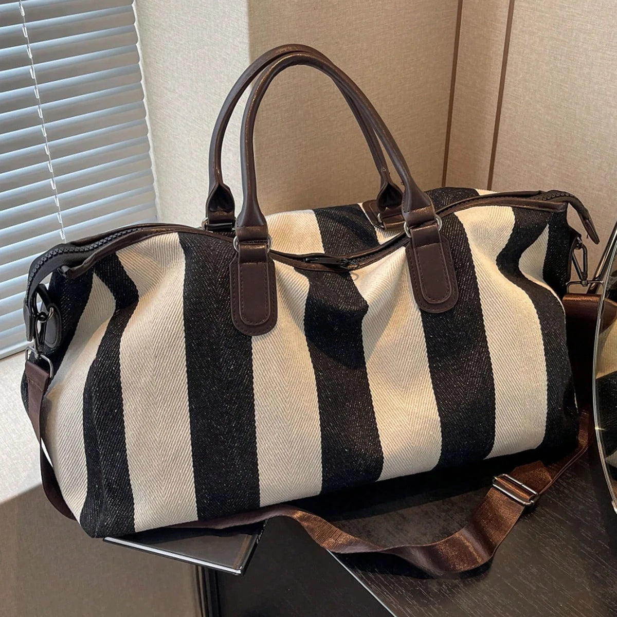 Striped weekender duffle bag with brown handles and adjustable shoulder strap