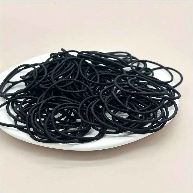 Black hair ties, loose pile of coiled elastic bands in dish