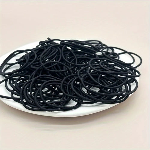 Black hair ties, loose pile of coiled elastic bands in dish