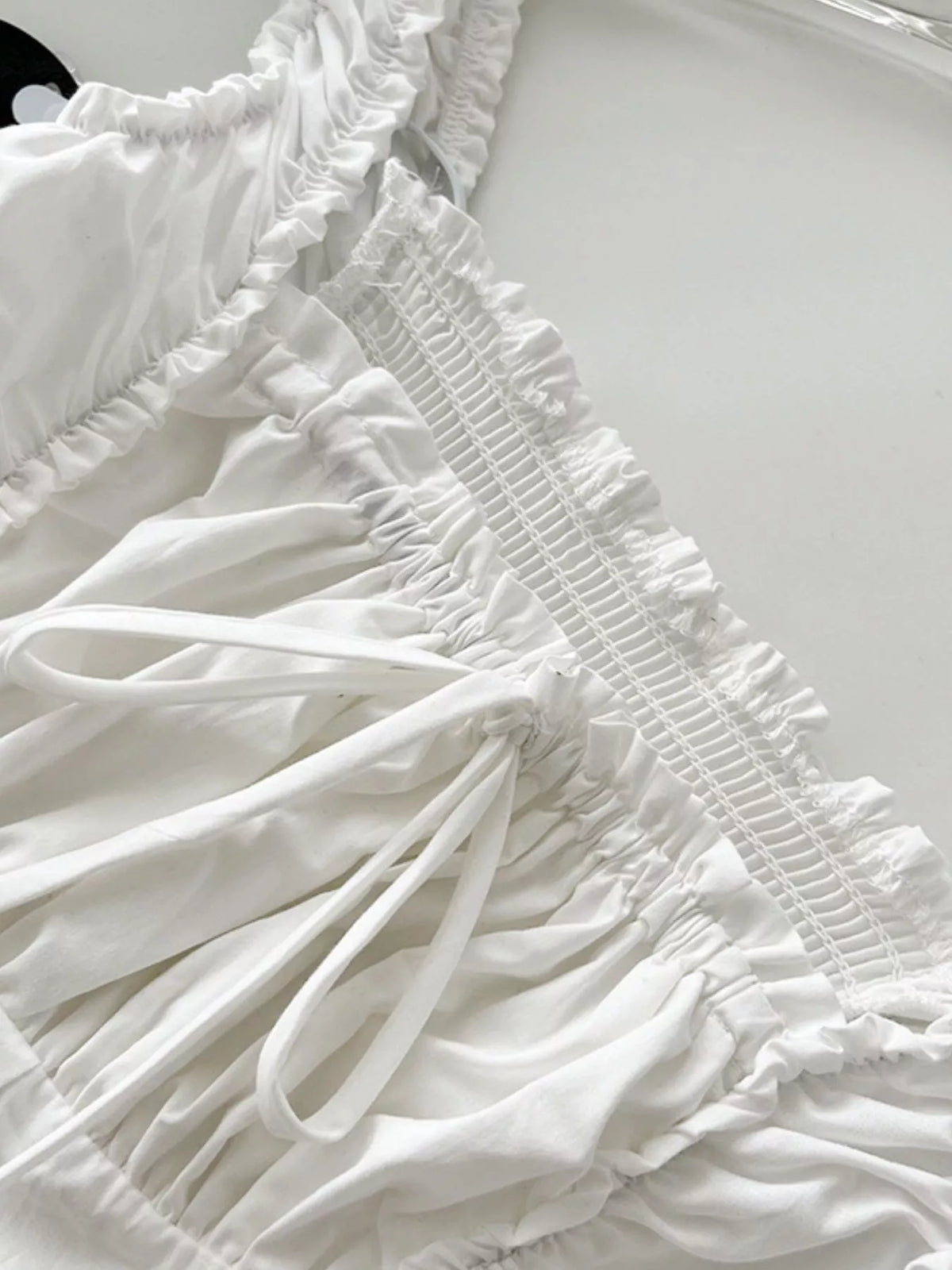 White cotton tiered ruffle dress detail with smocked bodice and gathered fabric tiers