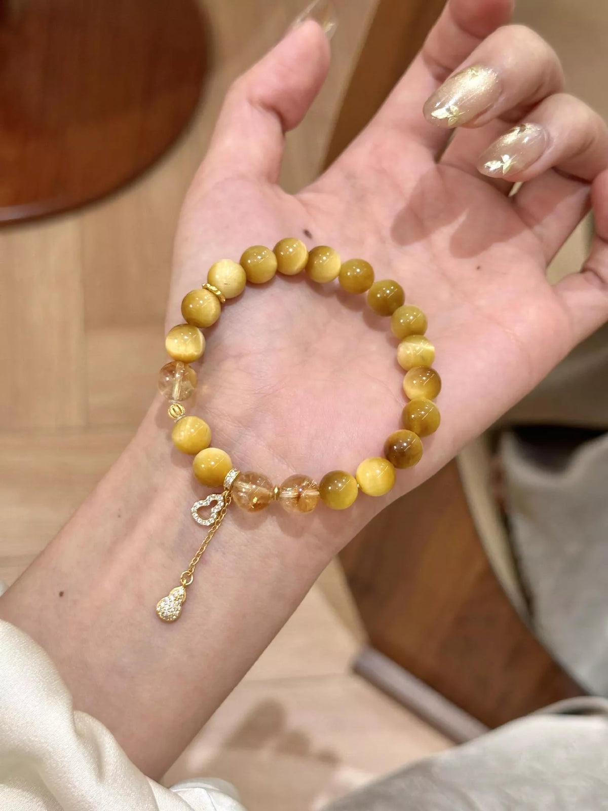 Beaded bracelet on palm, round amber beads with dangling gourd charm