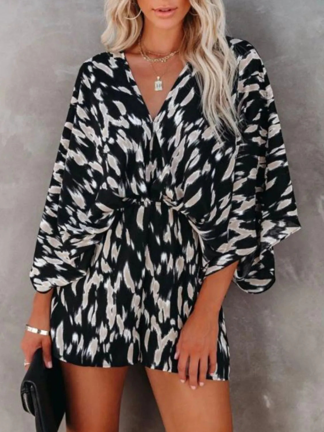 Leopard printed romper with V-neck, waist tie, and flowing oversized sleeves